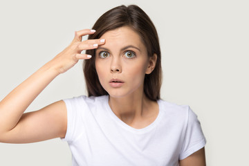 Headshot of surprised millennial woman notice first wrinkles on forehead