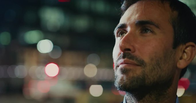 Slow motion of close up of young handsome businessman is looking around in a busy city center with traffic by night . Shot in 8K. Concept of business and finance, success, monopoly,wall street