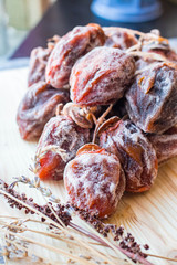 Dried sweet persimmon on wooden board with natural sugar layer. Vegan dessert.
