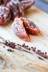 Dried sweet persimmon on wooden board with natural sugar layer. Vegan dessert.
