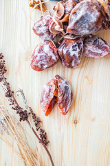 Dried sweet persimmon on wooden board with natural sugar layer. Vegan dessert.