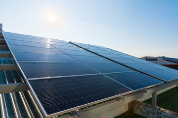 Obraz premium Solar panels and blue sky with light flare background.Solar cells farm on the roof.Photovoltaic modules for renewable energy.Save the earth and the energy with good environment concept.