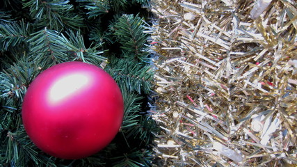 a red bauble in a close-up on a Christmas tree with a golden garland