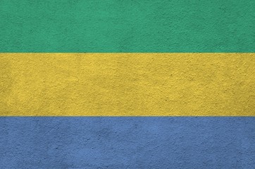Gabon flag depicted in bright paint colors on old relief plastering wall. Textured banner on rough...