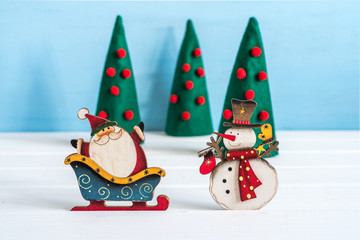 Miniature Santa Claus and Snowman on winter background.