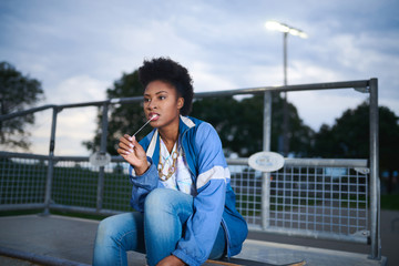 Attractive young african american woman skaterboarder blowing bu