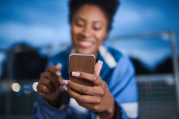 Attractive young african american woman skaterboarder using a mo