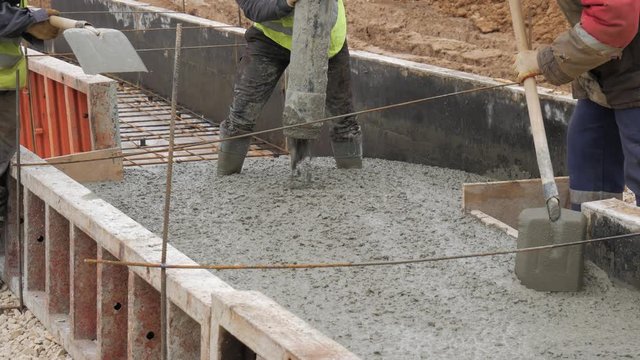 Pouring concrete mix from cement mixer on concreting formwork. Finished leveling the slab and pouring the concrete basement floor. 4K