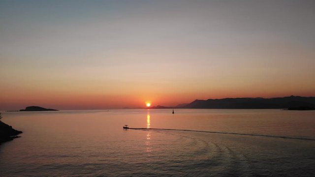 Wide aerial dolly shot of the last of the sunset tracking a small fishing boat, calm Adriatic seas, and beautiful seascape of the Croatian Coastline from Cavtat.