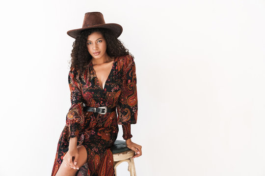 Image of african american cowgirl in dress and hat sitting on chair
