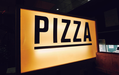 A trendy iconic cinematic typist font new york pizza sign inside a retro vintage hipster pizza diner in a city. Pop up eatery style pizza counter.