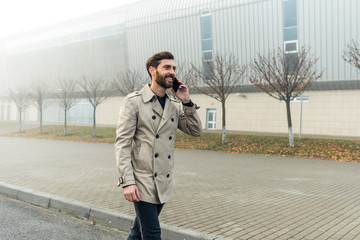 Fototapeta premium Young casual businessman using smartphone in the urban environment.
