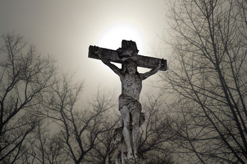 Sculpture of the crucifixion of Jesus on a background of foggy sky
