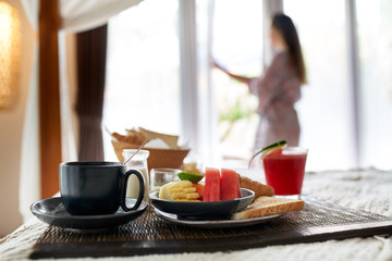 Modern vegan breakfast and cappuccino on hotel bed with female o