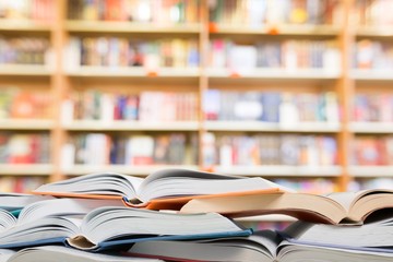 Many open books lying flat before a blue background with various formulas and letters.