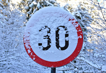 a speed limit indicator at 30 km / h covered with snow
