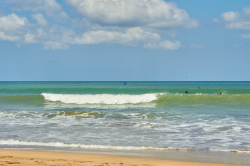 Beautiful ocean beach with sand, colored ocean water and blue sky with clouds in sunny day. Natural background for summer vacation.