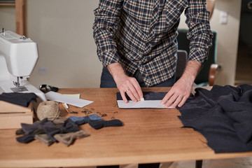 Tailor cutting wool fabric. the line pattern. Craftsman Makes rectangular blanks for Bow ties of woolen fabric. Work with sewing machine in a textile studio.