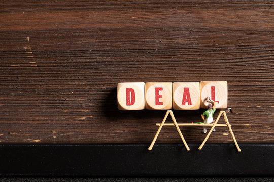 little painter figure and wooden blocks with the word "deal" on wooden background