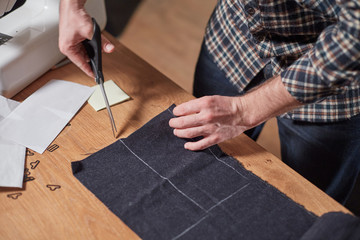 Closeup Tailor cutting wool fabric. the line pattern. Craftsman Makes rectangular blanks for Bow ties of woolen fabric. Work with sewing machine in a textile studio.
