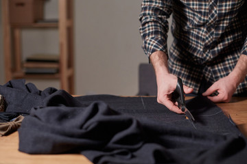 Closeup Tailor cutting wool fabric. the line pattern. Craftsman Makes rectangular blanks for Bow ties of woolen fabric. Work with sewing machine in a textile studio.