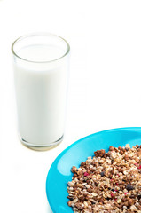 Muesli flakes in blue plate and glass of milk on white background selective focus