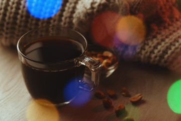 Cozy romantic composition of transparent cup of hot black coffee and small portion of roasted peanuts