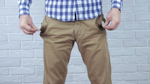 Broke young man showing his empty pockets.