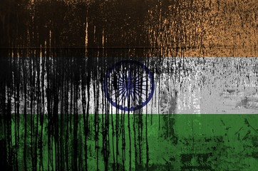 India flag depicted in paint colors on old and dirty oil barrel wall closeup. Textured banner on rough background