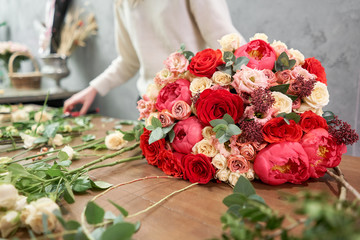 European floral shop concept. Florist woman creates red beautiful bouquet of mixed flowers. Handsome fresh bunch. Education, master class and floristry courses. Flowers delivery. - obrazy, fototapety, plakaty