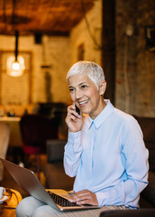 Senior businesswoman talking on phone in cafe.