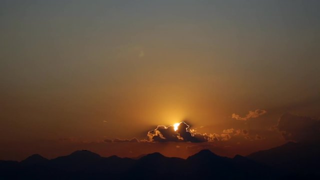 Beautiful great dramatic bright golden sunset landscape. Black silhouettes of airplanes flying down, sun slowly hiding behind mountains. Time lapse full hd video footage.