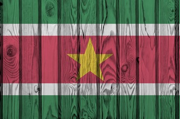 Suriname flag depicted in bright paint colors on old wooden wall. Textured banner on rough...