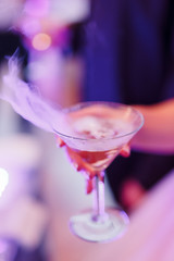 The bride holds a glass with champagne in her hand. Close-up shot of hands, tossing glass of alcohol at a party or event.