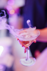 The bride holds a glass with champagne in her hand. Close-up shot of hands, tossing glass of alcohol at a party or event.