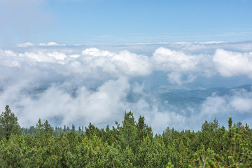View over the clouds, distant land far away. Astonishing clouds on sky. Mountain scenery.  Selective focus