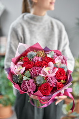 European floral shop. Beautiful bouquet of mixed flowers in womans hands. the work of the florist at a flower shop. Delivery fresh cut flower.