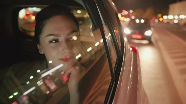Young beautiful woman in the backseat of the taxi is looking through the window