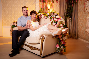 Obraz premium Happy beautiful cute young couple together in nice romantic room full of flowers. Love, celebration, romantic, st. Valentine's day, women day, birthday, date