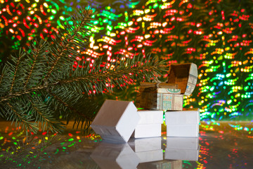 Cardboard boxes with gifts. Against the background of a fir branch and rainbow bokeh.