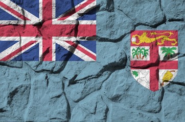 Fiji flag depicted in paint colors on old stone wall closeup. Textured banner on rock wall...