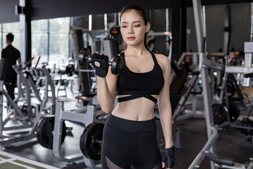Fototapeta na wymiar Asian women with dumbbells in the gym.