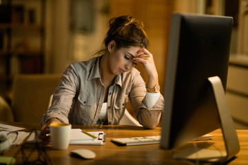 Young female student feeling tired while learning on a computer late at night.