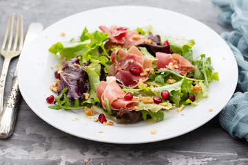salad prosciutto with pomegranate on white plate