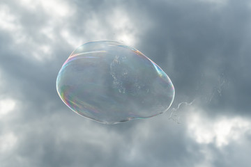 One big soap bubble in front of cloudy sky