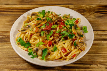 Pasta with mushrooms and tomato sauce on wooden table