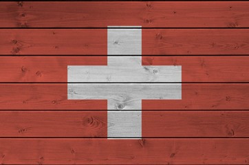 Switzerland flag depicted in bright paint colors on old wooden wall. Textured banner on rough...