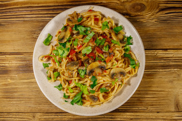Pasta with mushrooms and tomato sauce on wooden table. Top view