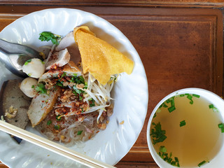 Dry pork noodles with a drink on a wooden table
