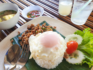 Pork fried rice and fried egg with a drink on a wooden table